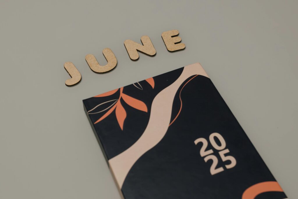 A modern 2025 planner with wooden 'June' letters on a minimalist background.